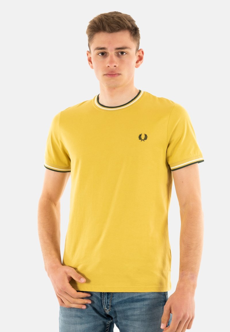 Camiseta de algodón amarilla con mangas cortas, cuello de canalé con franjas verdes y blancas, y un pequeño logo oscuro en el pecho.