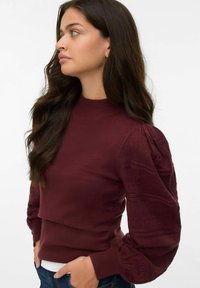 Pull bordeaux à col haut et à manches bouffantes texturées. Tissu en maille doux avec des poignets côtelés et un détail de couture superposé à la taille.