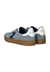 Zapatillas de ante gris con acentos blancos y suela de goma marrón. Presentan un logo lateral azul y el texto "SKECHERS" en el talón.