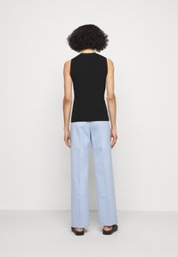Czarny top bez rękawów zestawiony z jasnoniebieskimi, szerokimi spodniami z wysokim stanem, o gładkiej fakturze i luźnym kroju.