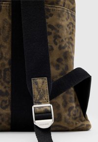 Borsa con stampa leopardata marrone e tracolla in cotone nero, caratterizzata da una fibbia metallica e dettagli di cucitura. Texture liscia, forma strutturata.