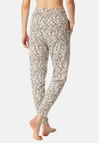 Pantalons légers et doux en tissu crème avec un motif floral bleu et marine. Design à jambes effilées avec poches latérales.