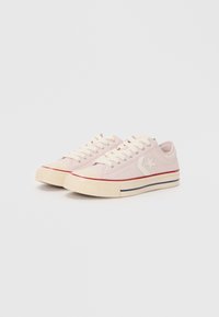 Sneakers in tela di un rosa chiaro con lacci bianchi, punta in gomma, strisce rosse e blu sulla suola e logo a stella sul lato.