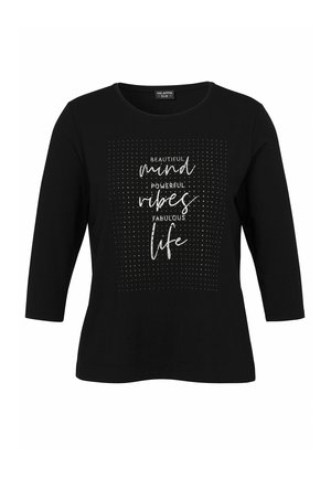 Schwarzes Shirt mit dreiviertel Ärmeln, versehen mit einem silbernen gepunkteten Quadrat und dem Text "Beautiful mind, powerful vibes, fabulous life" in Schriftzug und Druck.