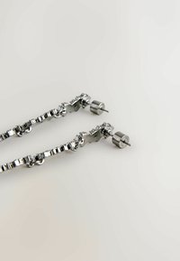 Orecchini a catena in argento con un design testurizzato, dotati di piccole chiusure a perno circolari e un motivo a catena collegata. Finitura metallica lucida.