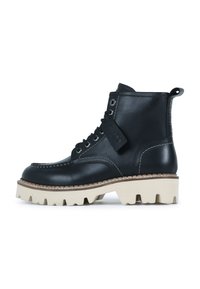 Bota de tobillo de piel negra con suela gruesa blanca, cordones negros, costuras en contraste y un tirador en el talón.