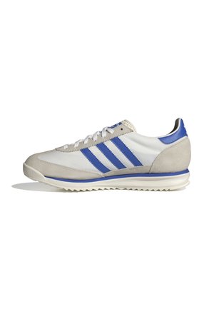 Hvid og grå atletisk sneaker med blå striber og blå hælkappe, snøredesign og rillede såler, vist fra siden på en hvid baggrund.