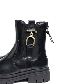 Black leather ankle boot featuring a gold-tone accent and elastic side panel, with a textured surface and a thick, sturdy sole.