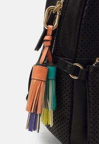 Svart perforerad läderryggsäck med färgglada lädertasslar i orange, teal, gult och lila, med guldfärgade detaljer.