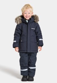 Manteau d'hiver bleu marine avec une capuche doublée de fausse fourrure, accompagné de pantalons assortis. Comprend des bandes réfléchissantes et une fermeture éclair.