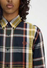 Camicia a quadri button-up in verde, giallo, nero e bianco. Presenta un logo ricamato, maniche lunghe e colletto classico.