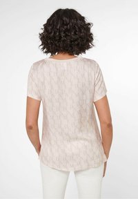 Lichtroze blouse met korte mouwen en subtiel reliëfpatroon met letters. Glad materiaal, gebogen zoom en een relaxed pasvorm.
