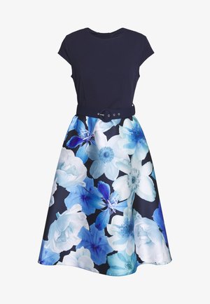 Granatowa sukienka z rękawami typu cap, dopasowanym gorsetem, czarnym paskiem oraz rozkloszowaną spódnicą z dużym, białym i niebieskim kwiatowym wzorem.