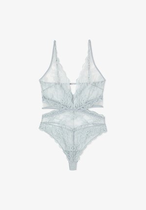 Zestaw bielizny koronkowej w jasnoniebieskim kolorze z głębokim dekoltem w kształcie litery V, wycięciami i kwiatowymi wzorami, ułożony płasko na białym tle.