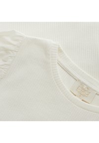 Strukturierter off-white Stoff mit gerippten Bereichen und einem Rüschendetail an den Ärmeln. Enthält ein kleines Markenlabel in der Nähe des Ausschnitts.