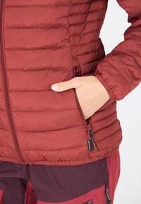 Burgunderfarvet isoleret jakke med vandret syninger, lynlåslommer, elastiske manchetter og en blød tekstur, designet til varme og komfort.