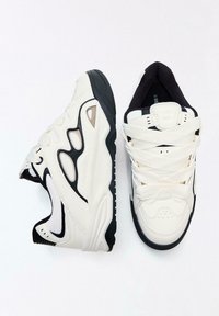 Fehér sportcipő fekete részletekkel, texturált anyagból, hálós betétekkel és vastag talppal. Keresztbe fűzött cipőfűzőkkel és párnázott szegéllyel rendelkezik.