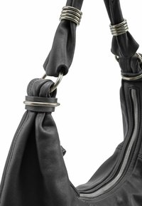 Borsa nera in pelle con tracolla annodata e dettagli con anelli metallici. Presenta una zip su un lato che mette in risalto la texture liscia.