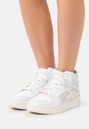 White high-top sneakers with a mix of smooth leather and soft suede. Features lace-up design and perforated toe for breathability.
