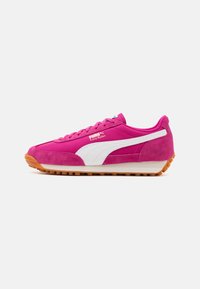 Puma Easy Rider -lenkkarit kirkkaan vaaleanpunaisesta mokasta valkoisilla yksityiskohdilla. Kengissä on kumipohja, jossa on teksturoitu pito ja klassinen nauhakiinnitys.