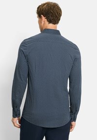 Marineblaues Langarmhemd mit geometrischem Muster, geknöpften Manschetten und abgerundetem Saum, aus einem leichten Stoff gefertigt.