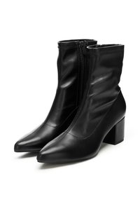 Paire de bottes mi-mollet en cuir noir avec bouts pointus, fermetures éclair latérales et talons carrés sur fond blanc.