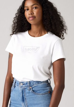 T-shirt en coton blanc avec un logo Levi's gris. Manches courtes et col ras du cou, associé à un short en denim bleu taille haute.