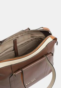 Bolso de piel marrón con un acento crema, cierre de cremallera y forro beige. Presenta una forma estructurada y una sola asa en la parte superior.