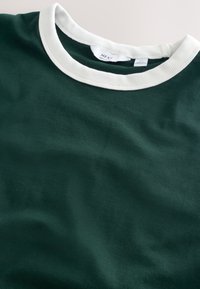 T-shirt vert foncé à col rond avec un col côtelé blanc et une étiquette de marque Next visible à l'intérieur du col.