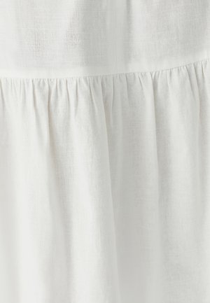 Weißes Leinenkleid mit einer strukturierten Oberfläche und gesammelten Details am Saum, die ein fließendes Erscheinungsbild erzeugen.