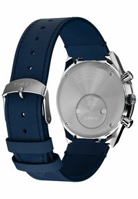 Tylnia część zegarka Timex z stalową kopertą, srebrnymi przyciskami oraz ciemnoniebieskim skórzanym paskiem z metalową klamrą wygrawerowaną napisem "TIMEX."