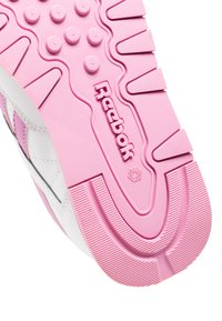 Roze Reebok-schoenen met een textuurpatroon op de zool, verhoogde ronde gripstukken, en het Reebok-logo gecentreerd ingeslagen.