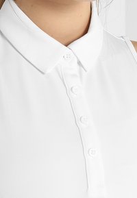 Bílá košile s límečkem a knoflíkovou légou se šesti knoflíky, hladkým povrchem a přiléhavým střihem.