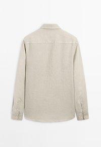 Beige lange mouwen overhemd van linnen. Voorzien van een spitse kraag, knoopmanchetten en een gebogen zoom. Zachte textuur met minimale details.