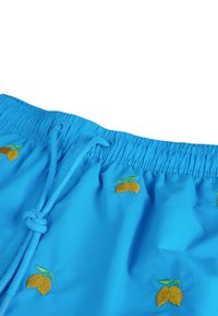 Pantaloni da bagno blu con cintura elasticizzata e cordoncino turchese, caratterizzati da ricami ripetuti di frutta gialla. Texture liscia.