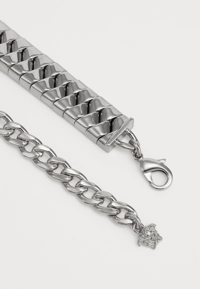 Brăță de lanț din argint, cu un design texturat și sculptat, prevăzută cu un închizător tip homar, având un charm decorativ în formă de cap de leu la capăt.
