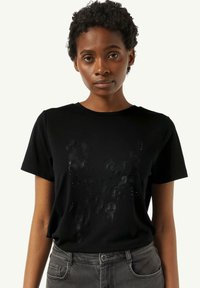 Czarna bawełniana koszulka z krótkim rękawem, z teksturowanym wzorem z przodu, z półprzezroczystymi akcentami i subtelnymi detalami graficznymi.