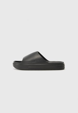 Black slide sandal with a textured upper, wide strap, and cushioned sole. The design features minimal branding on the side and a smooth finish.