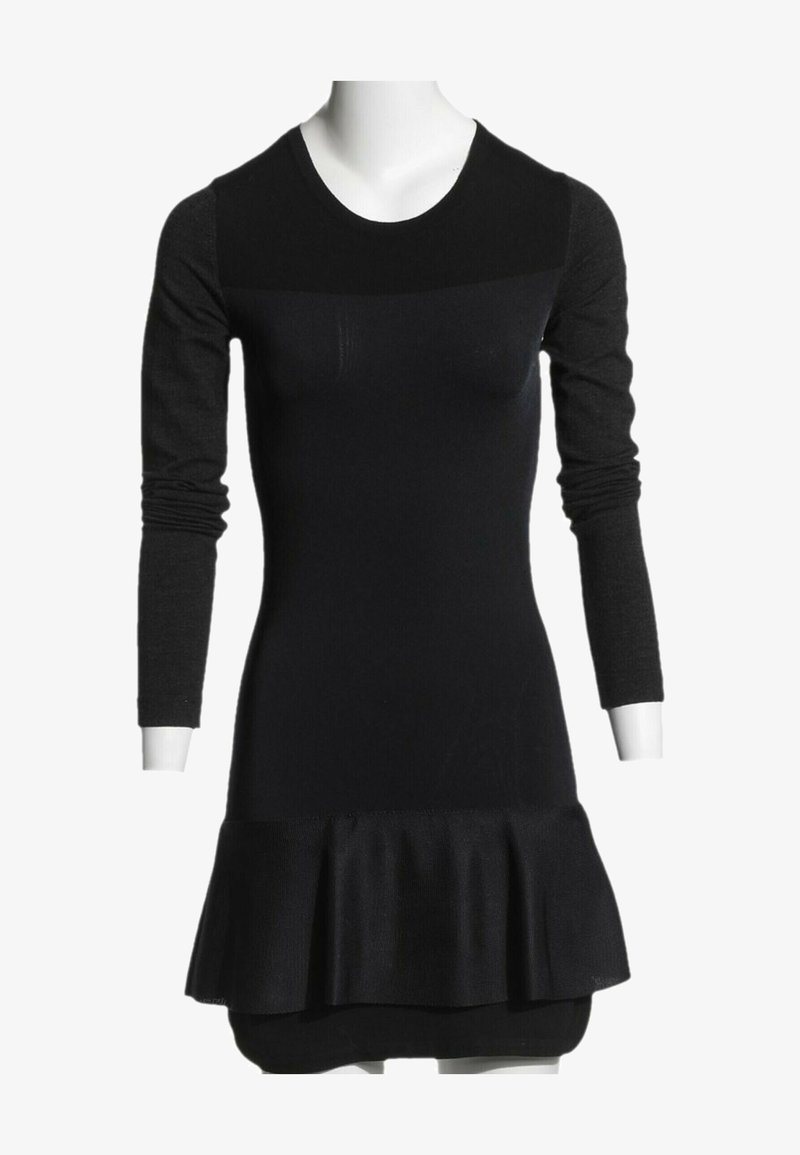 Robe noire ajustée à manches longues avec un col rond et un bas évasé à volants, présentée sur un buste de mannequin blanc.