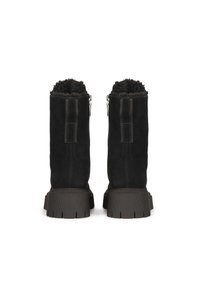 Botas de tobillo de ante negro con ribete de piel de oveja en la parte superior, con cierres de cremallera lateral y suelas de goma gruesas y estriadas.