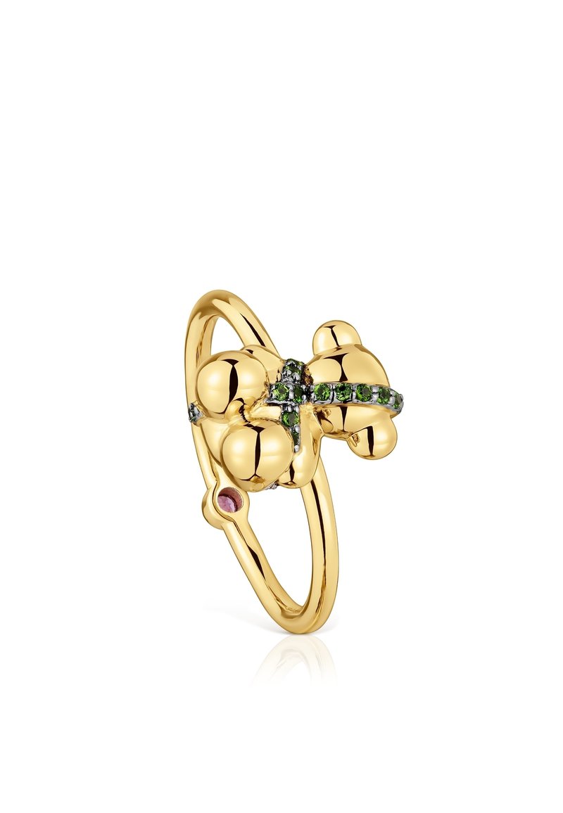 L'anello d'oro presenta un design arrotondato con gemme verdi e viola. È caratterizzato da una superficie liscia e un'unica decorazione centrale.