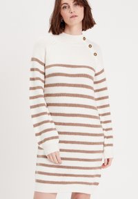 Robe pull tricotée présentant des rayures horizontales beige et blanches, une texture côtelée, un col montant et trois boutons dorés en accent sur l'épaule.