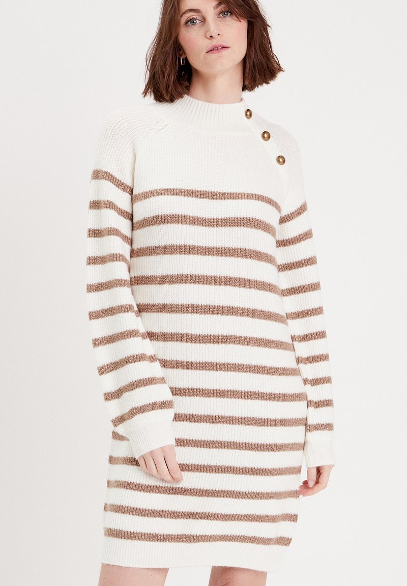 Robe pull tricotée présentant des rayures horizontales beige et blanches, une texture côtelée, un col montant et trois boutons dorés en accent sur l'épaule.
