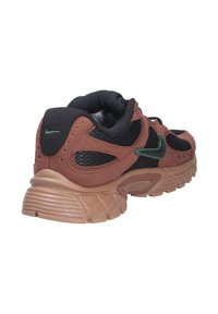 Bruine en zwarte sportschoen met mesh en suède materialen, groene accenten, een gevoerde zool en een gestructureerde hielpaneel.