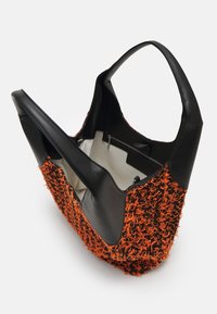 Borsa a tote con una base in pelle nera, caratterizzata da un'esterno in tessuto testurizzato arancione. Design a apertura superiore con un ampio interno crema e una tasca con zip.