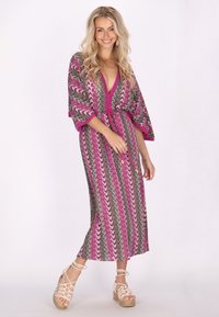 Dugi kimono haljina s vibrantnim uzorkom valova u ružičastoj i višebojnoj boji, širokim rukavima i vezanjem u struku. Teksturirana tkanina.