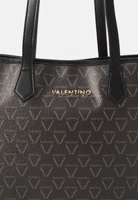Saco tote preto com acabamento texturizado, apresentando um padrão repetido de logótipos em "V", alças em couro e um detalhe em tom dourado com o logótipo "Valentino".