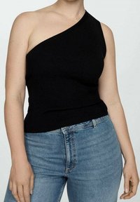 Camiseta sin mangas negra acanalada con un diseño asimétrico de un solo hombro. Combinada con jeans de talle alto en azul claro. Textura suave y forma ajustada.