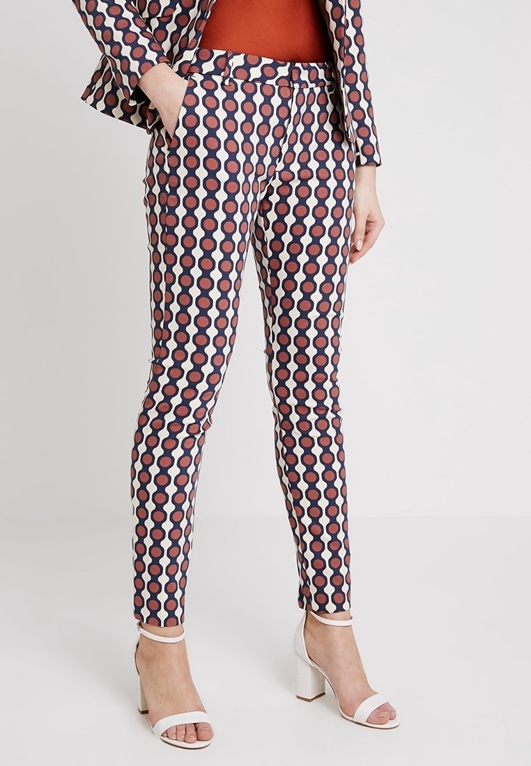 Pantalons à motifs présentant un design géométrique dans des teintes de bleu marine, rouge et crème. Coupe slim avec poches latérales et texture lisse.