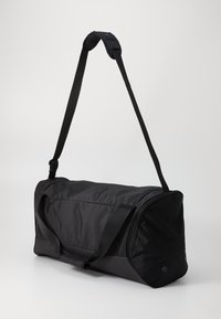 Black duffel bag with a rectangular shape, made of nylon. Features dual handles and an adjustable shoulder strap for versatile carrying.